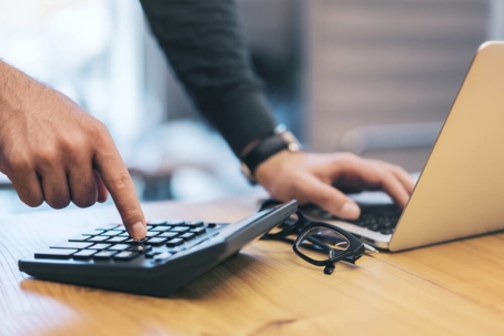 person using calculator and laptop