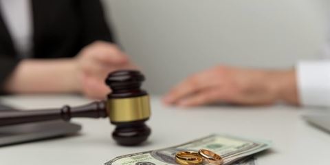 A gavel and money on a table between two people symbolizing alimony