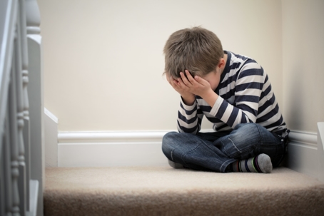 Boy sitting with his face resting in his hands.