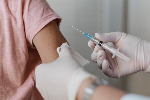 A child’s arm about to get injected with a vaccine.
